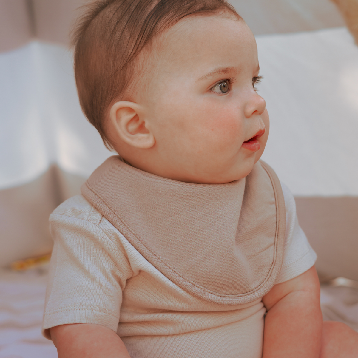 a baby wearing a cream coloured bib